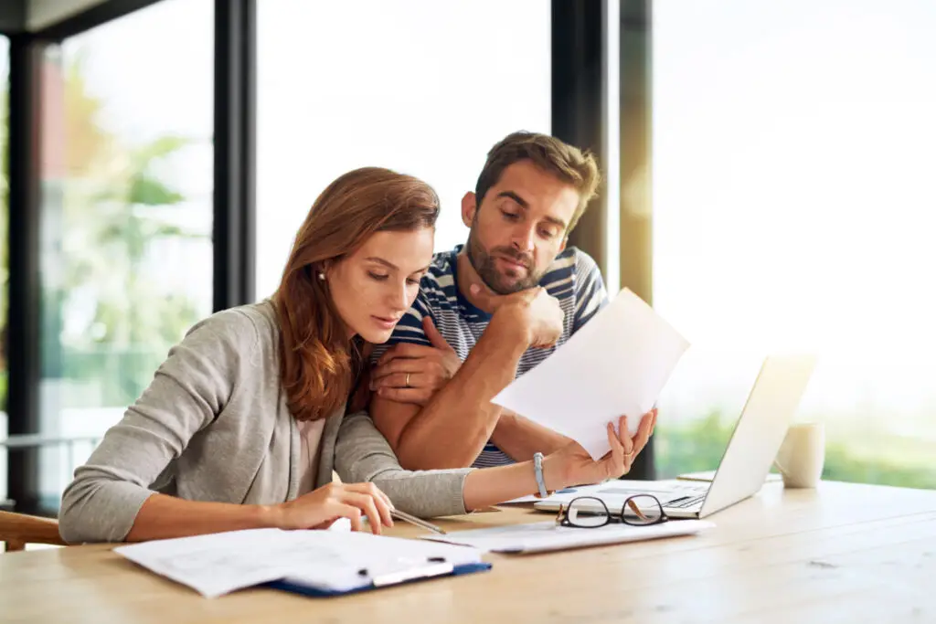 Couple reviewing loan paperwork together at a desk with a laptop
