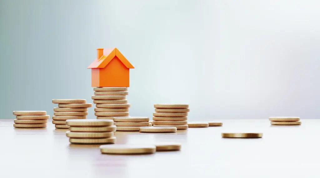 Small model house sitting on stacks of coins