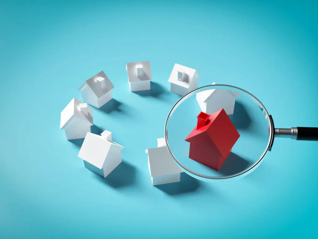 Magnifying glass highlighting one red model house among white model houses