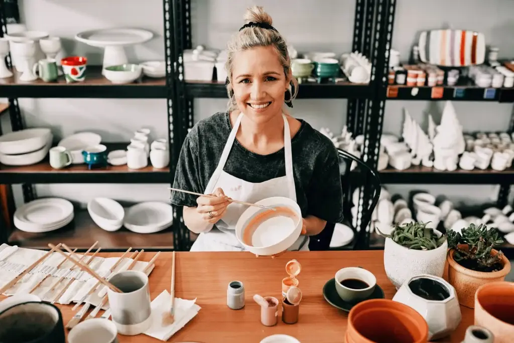 Small business owner smiling in her pottery studio surrounded by her work