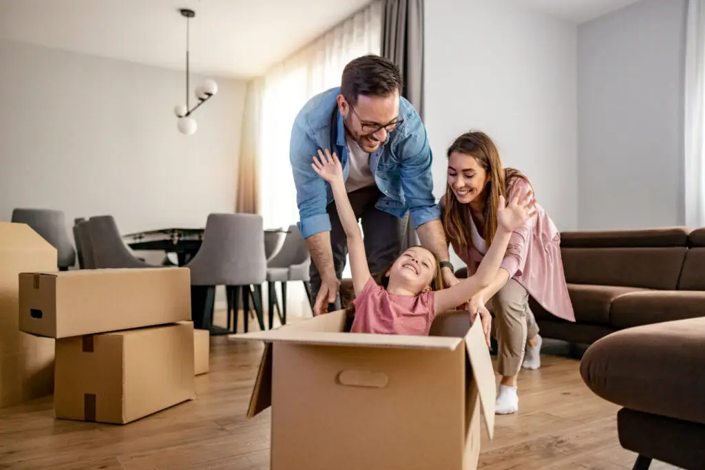 Young family unpacking moving boxes in the living room of their new home